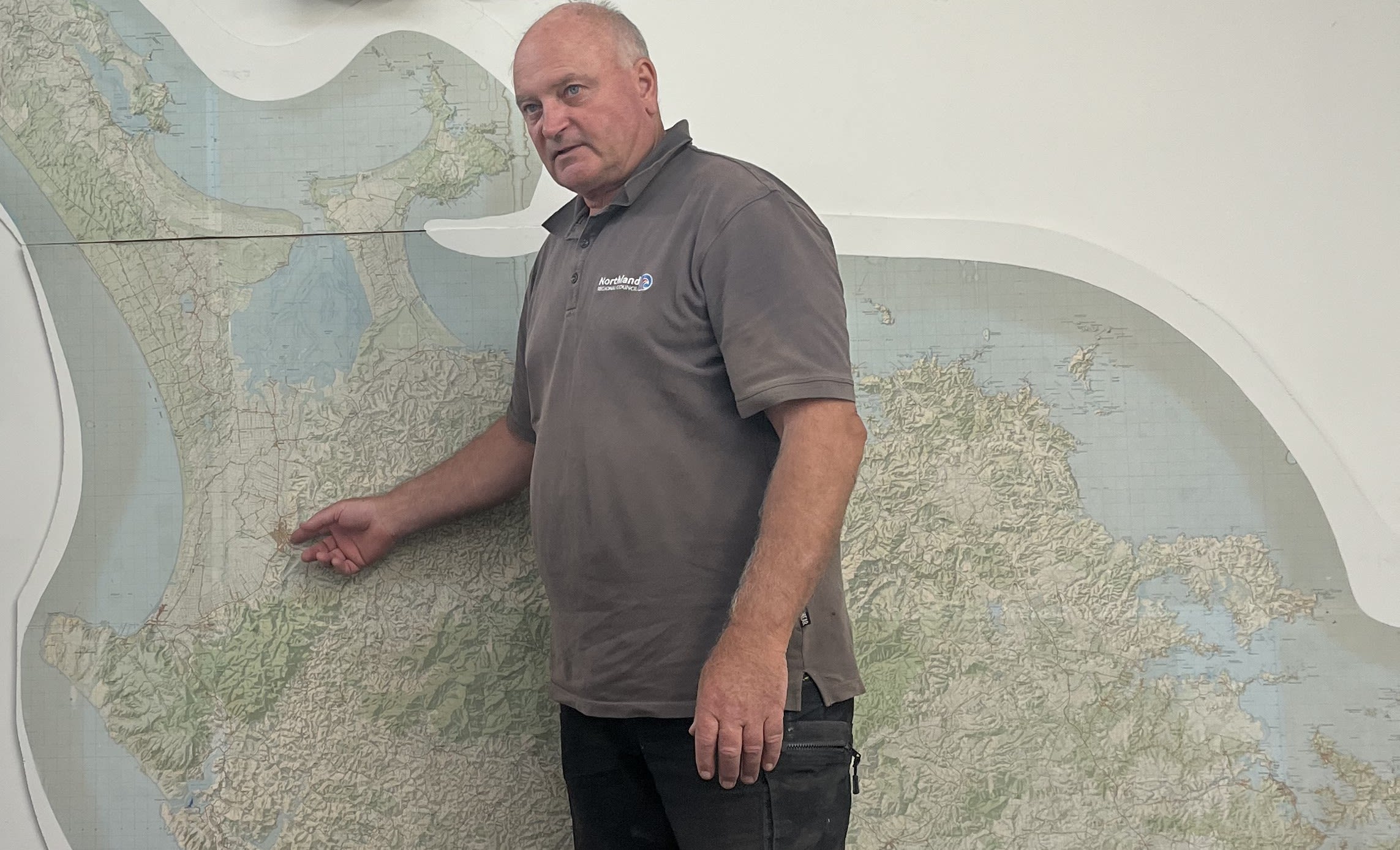 Man standing in front of wall map, pointing to one location.